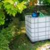 ibc-container-wit-met-pomp-220V-1000L-gereinigd-pallet-metaal-of-kunststof-linkeraanzicht-in-tuinomgeving.webp