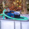 ibc-container-wit-met-pomp-accu-1000L-gereinigd-pallet-metaal-of-kunststof-rechterzijaanzicht-vooraanzicht-met-slang.webp