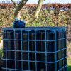 ibc-container-zwart-met-pomp-accu-1000L-vernieuwd-pallet-metaal-of-kunststof-zijaanzicht-achteraanzicht-zonder-uitgaande-slang-in-tuinomgeving.jpg