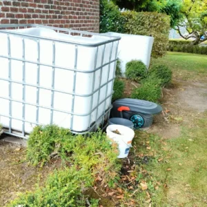 IBC container 1000 liter in de tuin gebruikt voor het verzamelen van bladeren, naast woning geplaatst