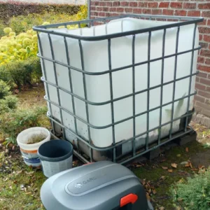 IBC container 1000 liter hergebruikt in de tuin voor bladeren en groenafval, naast tuingereedschap geplaatst