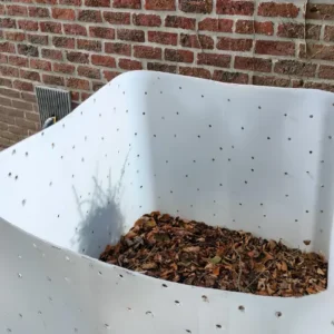 IBC container blaas hergebruikt als bladverzamelaar in de tuin, gevuld met herfstbladeren