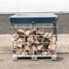 IBC container voor houtopslag buiten in de tuin, gevuld met droog brandhout en afgedekt met zeil