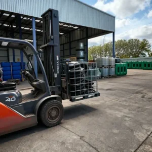 Kooi van een IBC container ingezet als transportbak voor putdeksels, verplaatst met heftruck op buitenterrein met opslagtanks